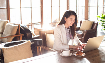 Woman accessing HSBC digital banking solutions via her laptop while at a café Woman accessing HSBC digital banking solutions via her laptop while at a café